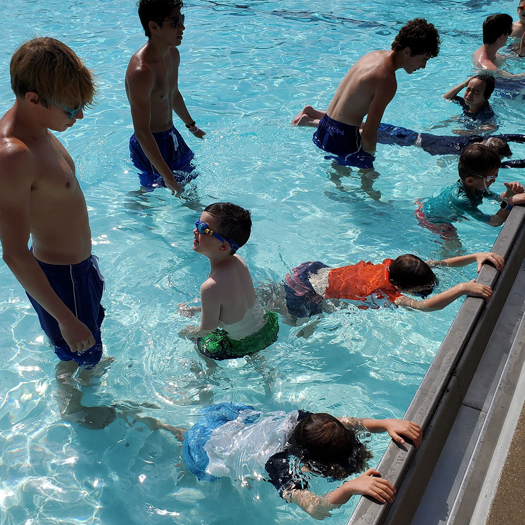 Instructor teaching kids to kick in the pool