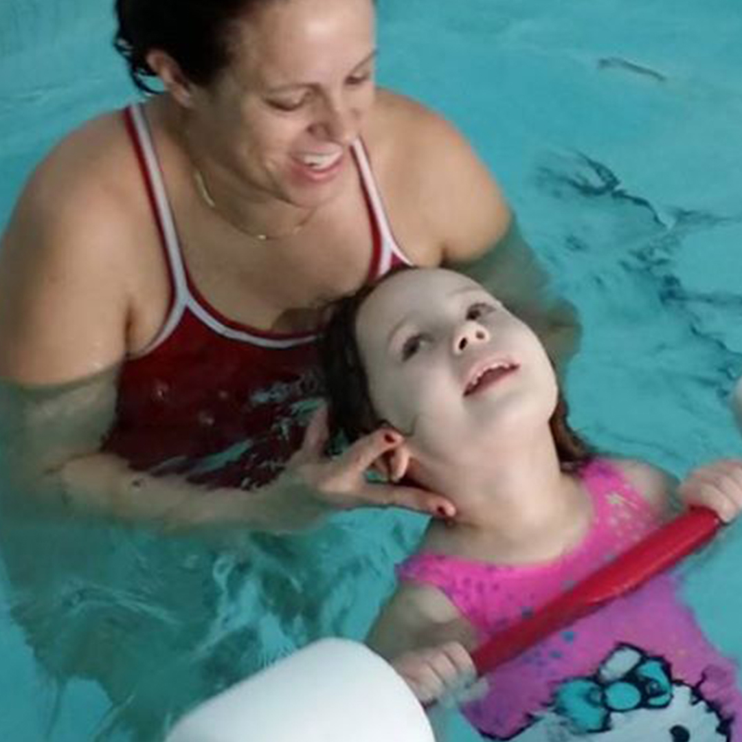 Instructor guiding preschooler while floating