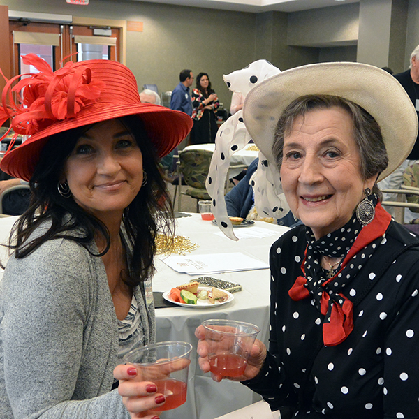 Two women in colorful hats smiling in Heritage