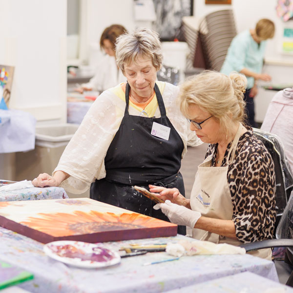 Two women painting on canvas with acrylic paint