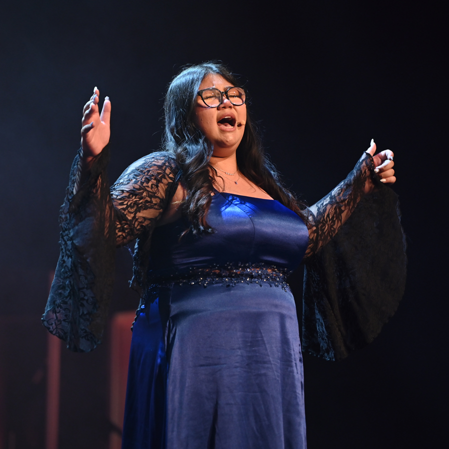 Magdalena singing with her arms open wide