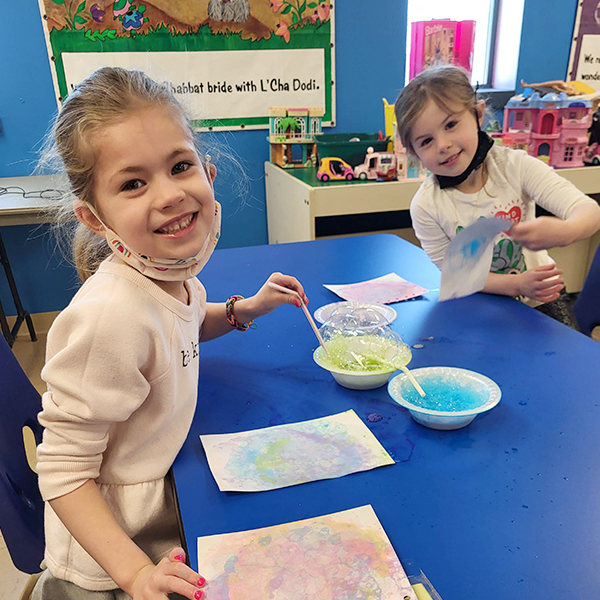 Girls painting watercolor with straws