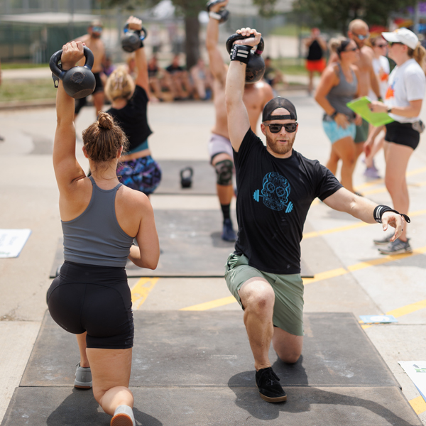CrossFit athletes doing lunge while raising a kettlebell