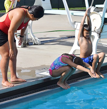 Kids sitting on edge of pool to dive in 
