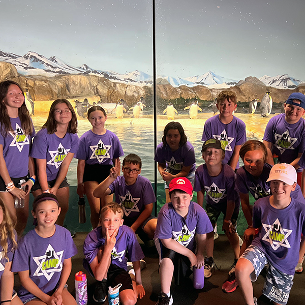 A group of camp children in front of the penguin exhibit at the zoo.