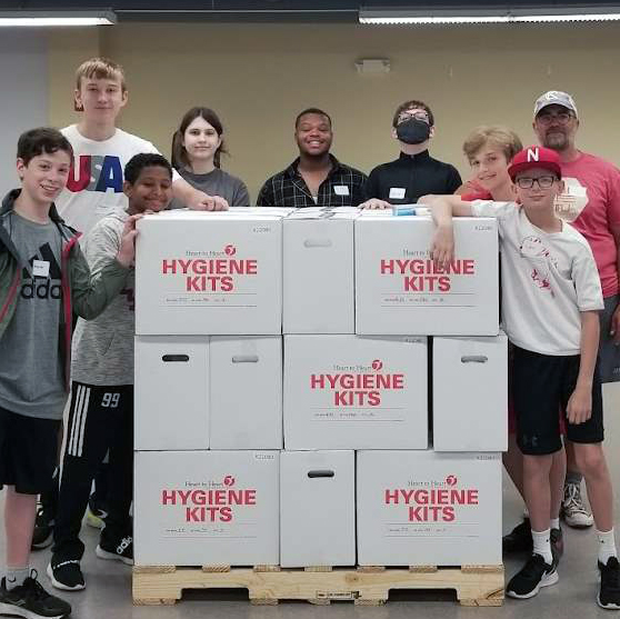 Group of camp children standing with a load of hygiene kits they just assembled.
