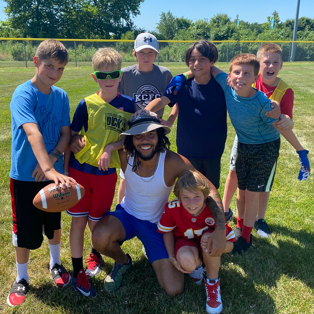 Group of boys around their coach, holding a football.
