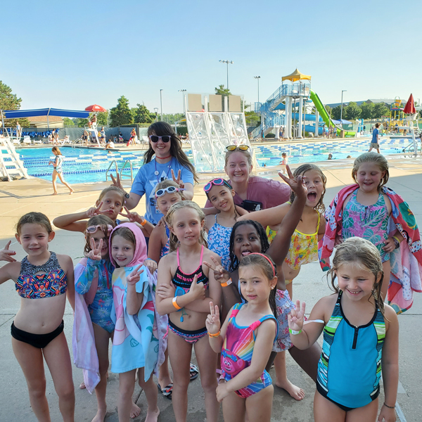 Campers posing with smiles by the outdoor pool