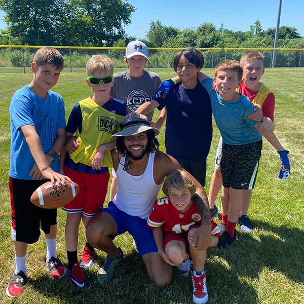 Group of boys around their coach, holding a football.