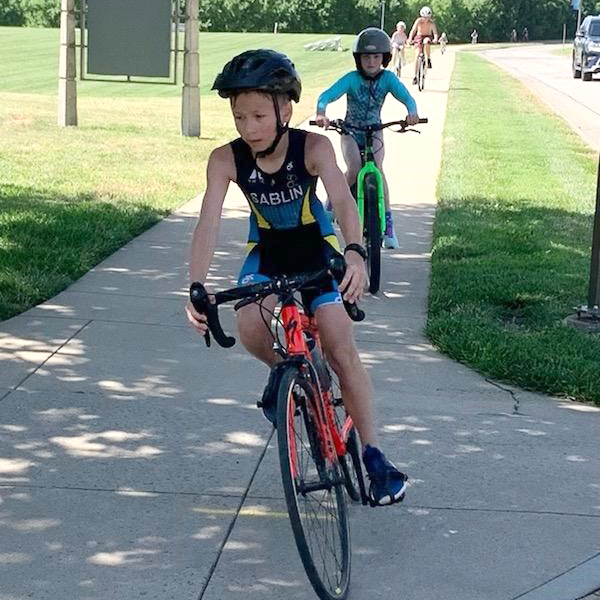 Children on bicycles follow the sidewalk path.