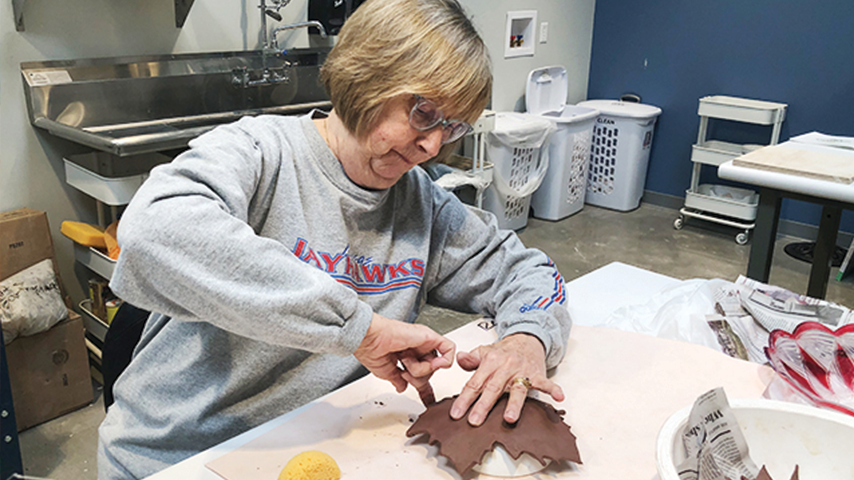 Woman shaping leaf out of clay