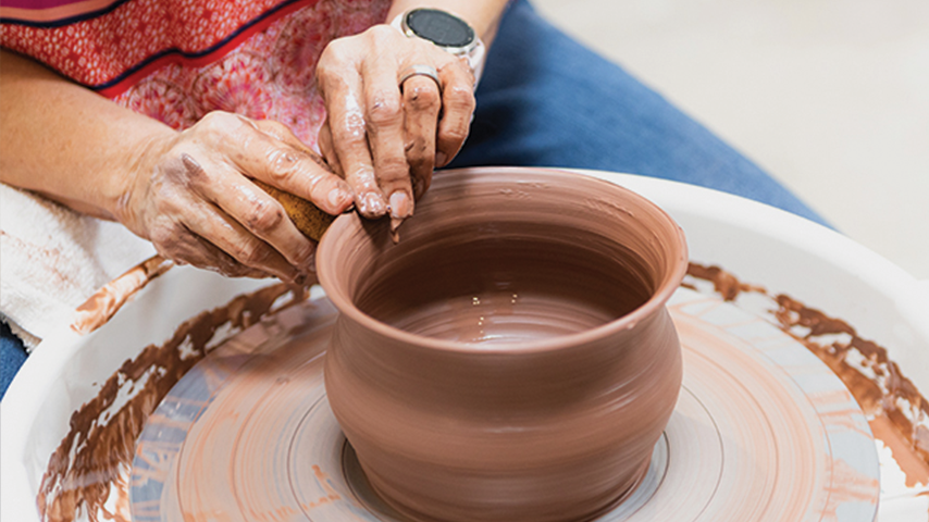 Photo of person making a vase on a wheel
