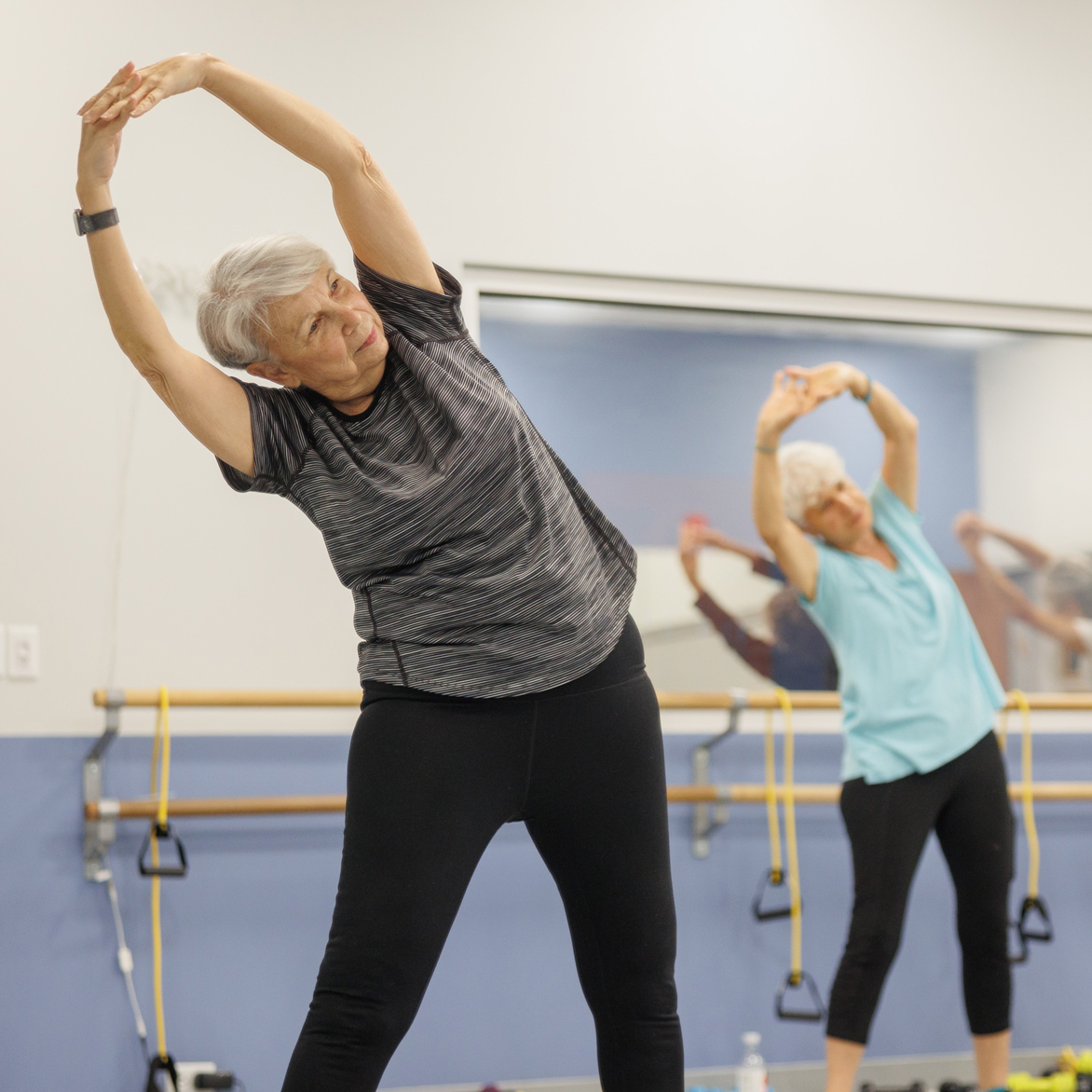 Women stretching with arms over head.