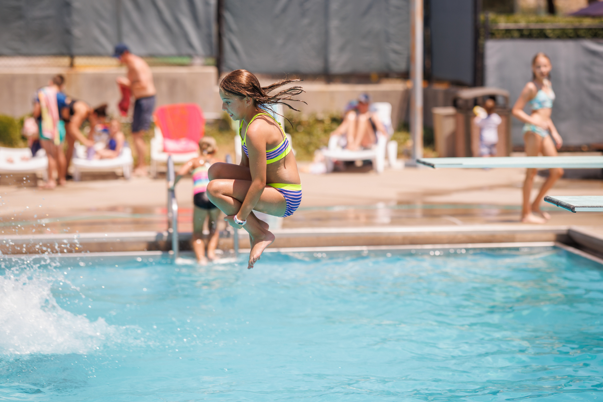 Girl jumping off diving board into the pool