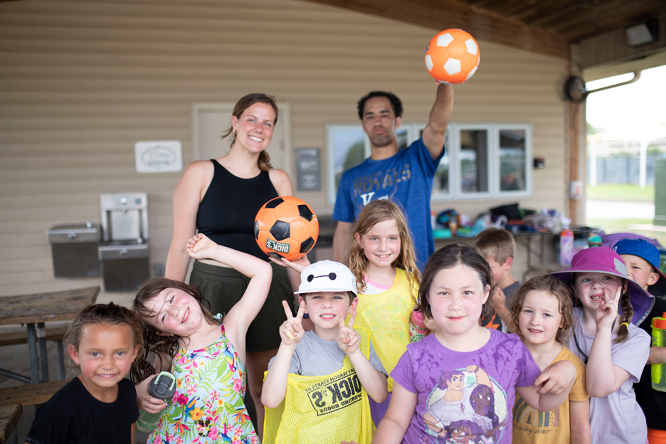 Counselors and campers with orange soccer balls smiling