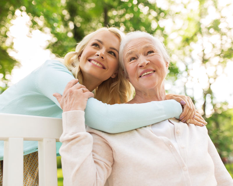 Woman in wheelchair with caregiver, both smiling