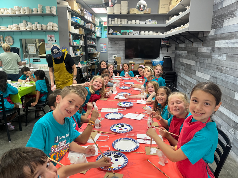 Girl sitting at pottery wheel smiling