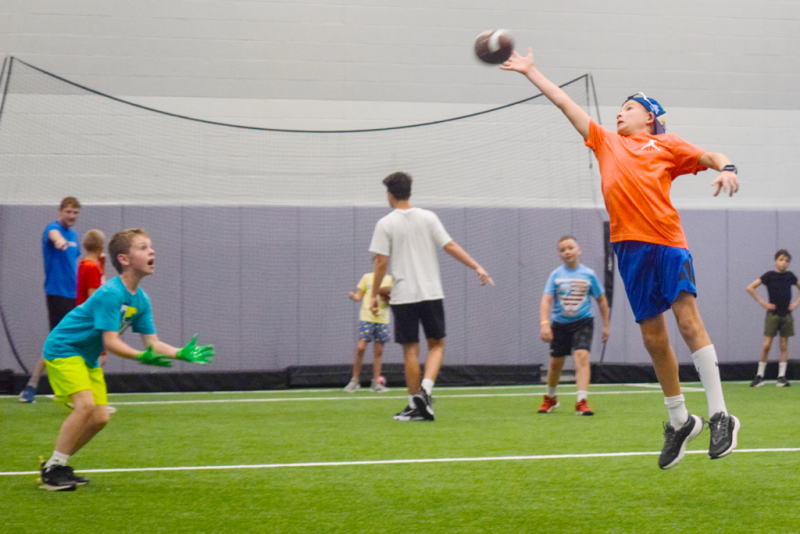 Boy reaching for a football in the air