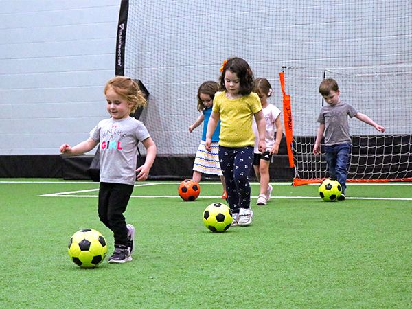 Kids on a turf with soccer balls