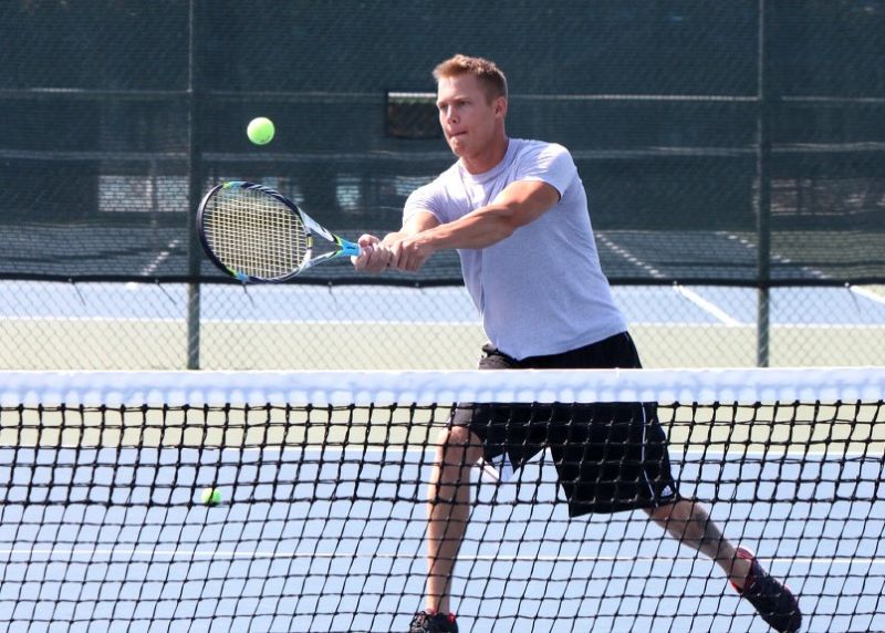 J member returns a serve in tennis match