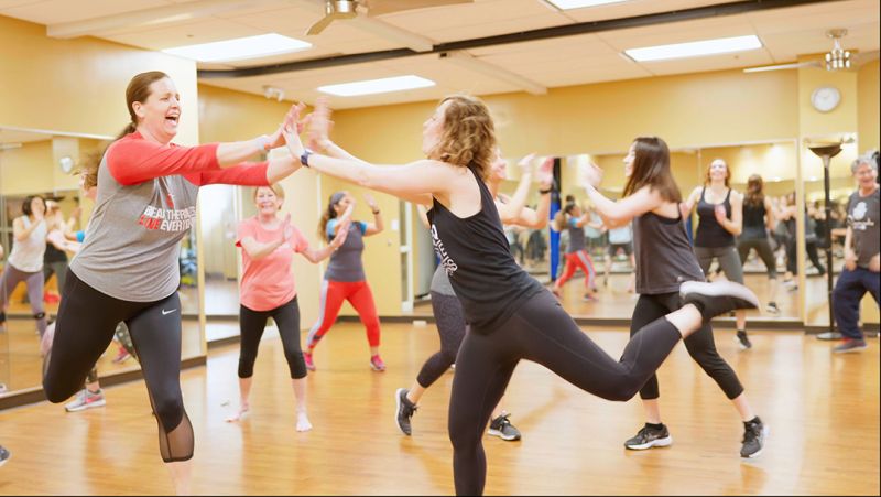 Two women dancing in Zumba class, giving a double high five.