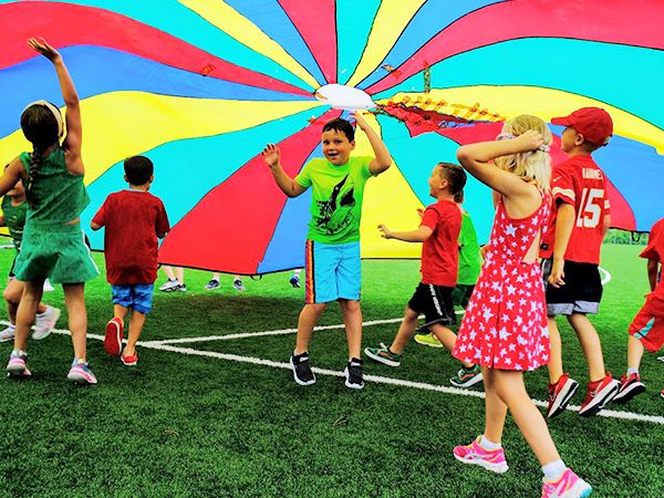Kids running under a colorful parachute