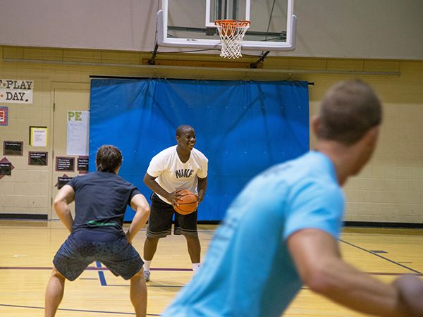 Man holding a basketball with an opponent ready to block him.
