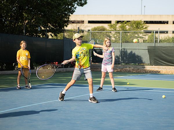 Boy swinging tennis racquet at ball