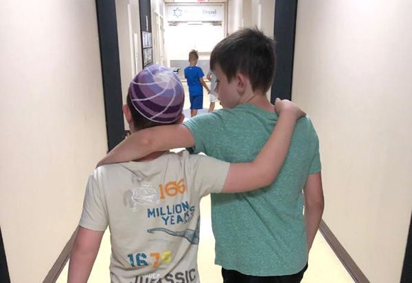 Two kids with arms over each other's shoulders